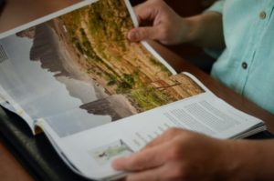 A woman reads a travel magazine and her attention is drawn to a tourist destination through print tourism advertising 
